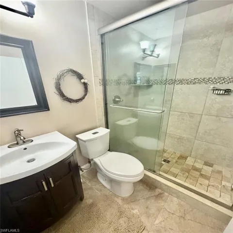 Bathroom with an enclosed shower, vanity, and toilet