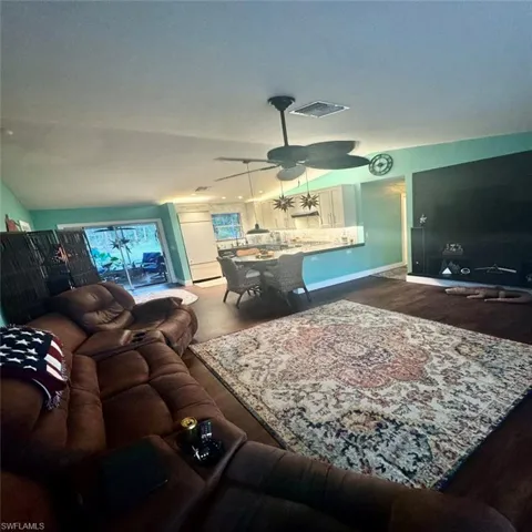 Living room with luxury Vinyl flooring, ceiling fan, and vaulted ceiling