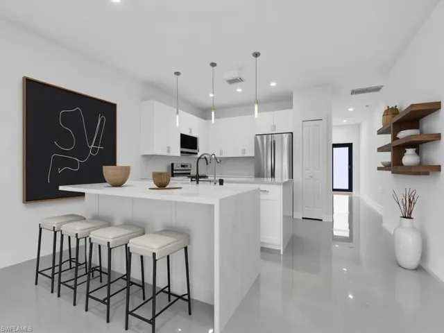 Kitchen featuring white cabinetry, a breakfast bar area, light stone counters, hanging light fixtures, and recessed lighting