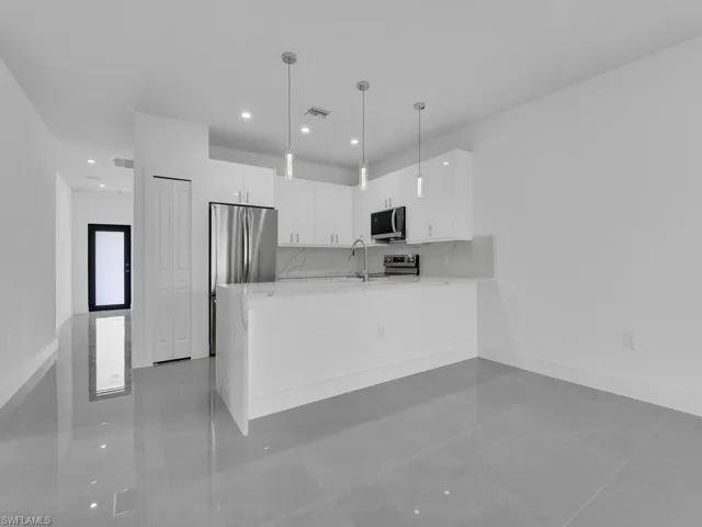 Kitchen with white cabinets, modern cabinets, hanging light fixtures, a peninsula, and stainless steel appliances