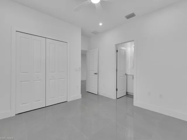 Unfurnished bedroom featuring light tile patterned flooring, ensuite bath, ceiling fan, a closet, and recessed lighting