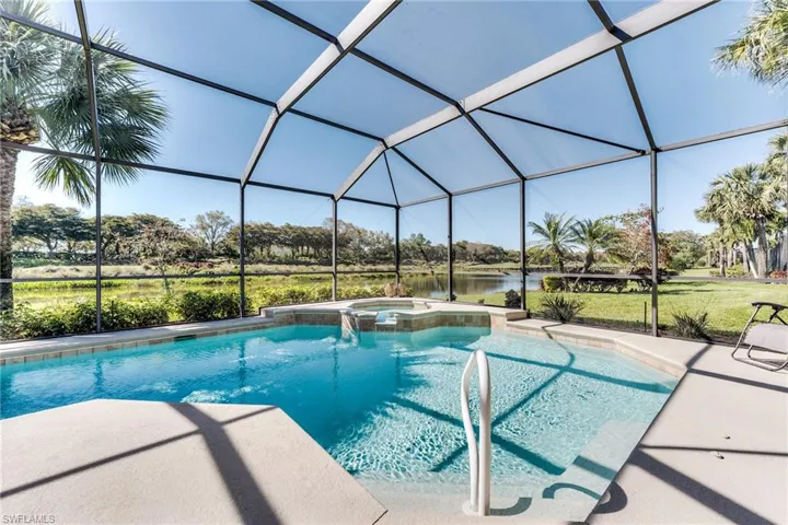 View of swimming pool with a patio area, a pool with connected hot tub, and glass enclosure