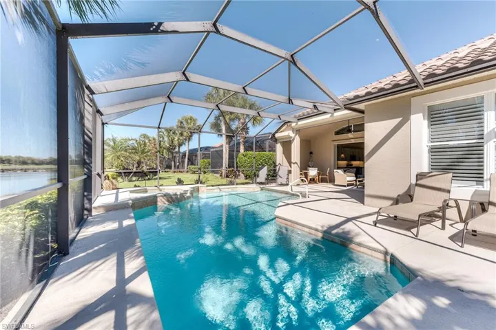 Outdoor pool featuring a ceiling fan, glass enclosure, and a patio area