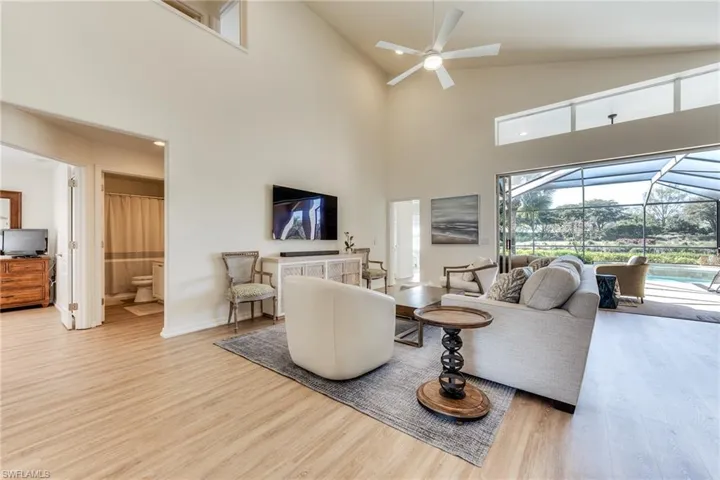 Living room with baseboards, a ceiling fan, lofted ceiling, a sunroom, and wood finished floors