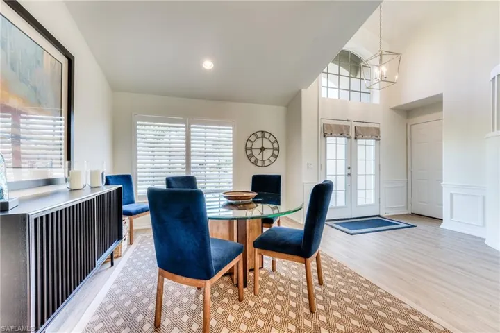 Dining room with a decorative wall, a wainscoted wall, wood finished floors, french doors, and an inviting chandelier