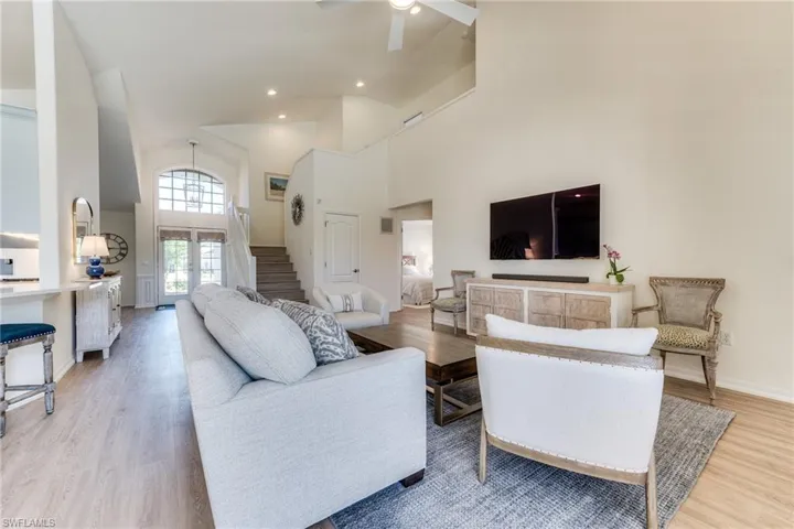 Living area with recessed lighting, a high ceiling, ceiling fan, light wood-type flooring, and stairs
