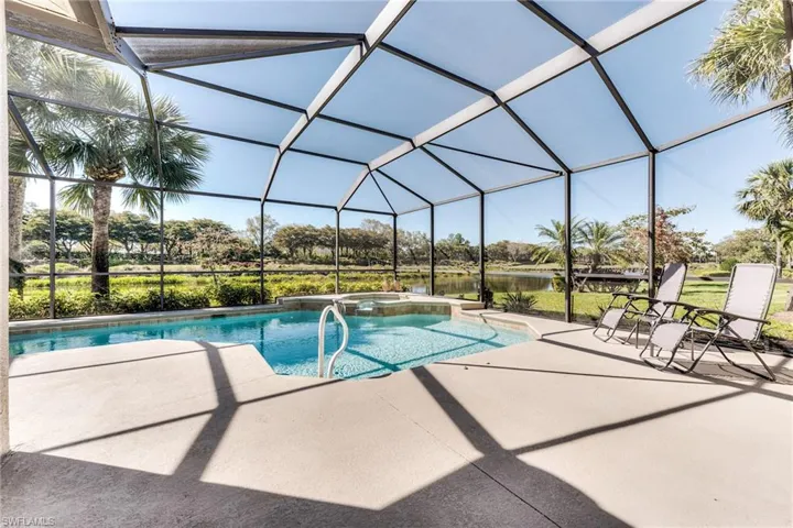 View of pool with glass enclosure, a pool with connected hot tub, and a patio