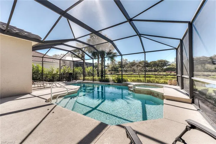 View of swimming pool with glass enclosure, a pool with connected hot tub, and a patio