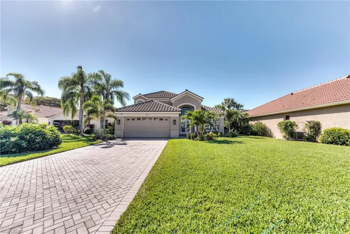 Mediterranean / spanish house featuring decorative driveway, a tile roof, stucco siding, a front yard, and a garage