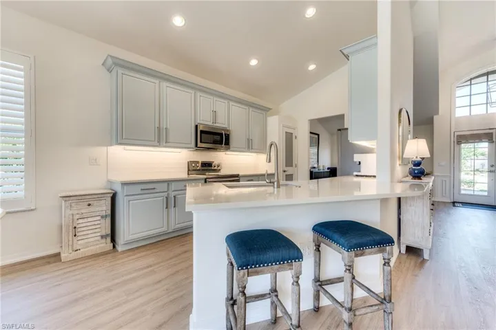 Kitchen with tasteful backsplash, gray cabinetry, appliances with stainless steel finishes, vaulted ceiling, and a sink
