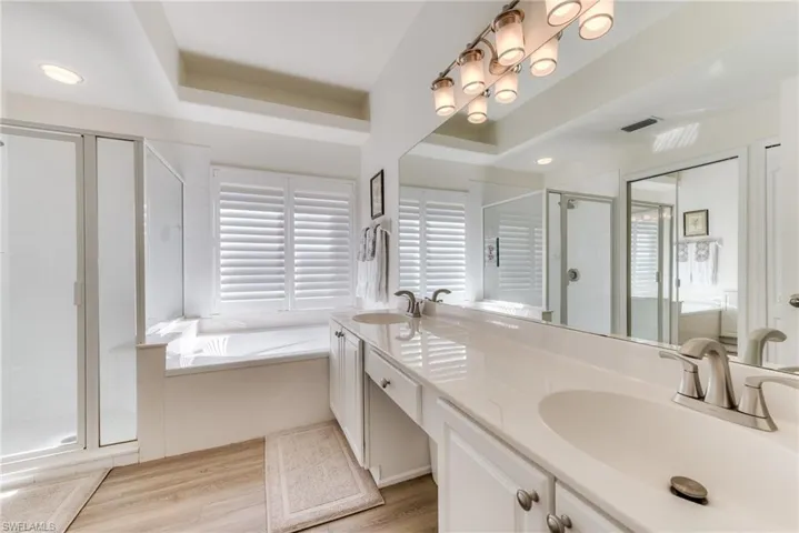 Bathroom featuring visible vents, a sink, a shower stall, and a garden tub