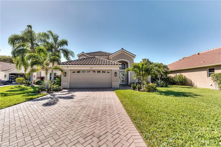 Mediterranean / spanish-style house with a garage, a tile roof, decorative driveway, a front lawn, and stucco siding