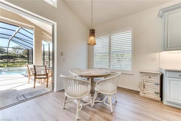 Dining area featuring vaulted ceiling, light wood-style floors, a sunroom, and a healthy amount of sunlight