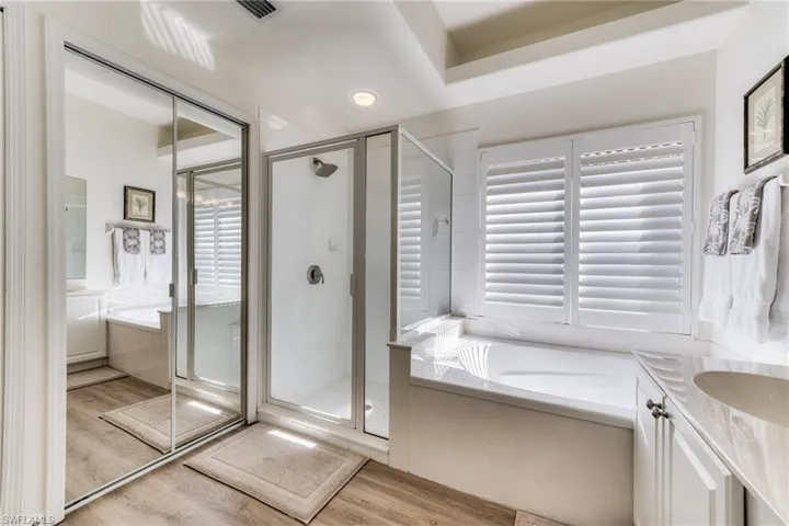 Full bathroom featuring a bath, a shower stall, wood finished floors, and vanity