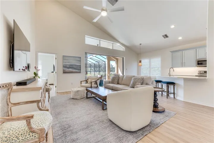 Living area featuring recessed lighting, visible vents, light wood-style floors, ceiling fan, and high vaulted ceiling