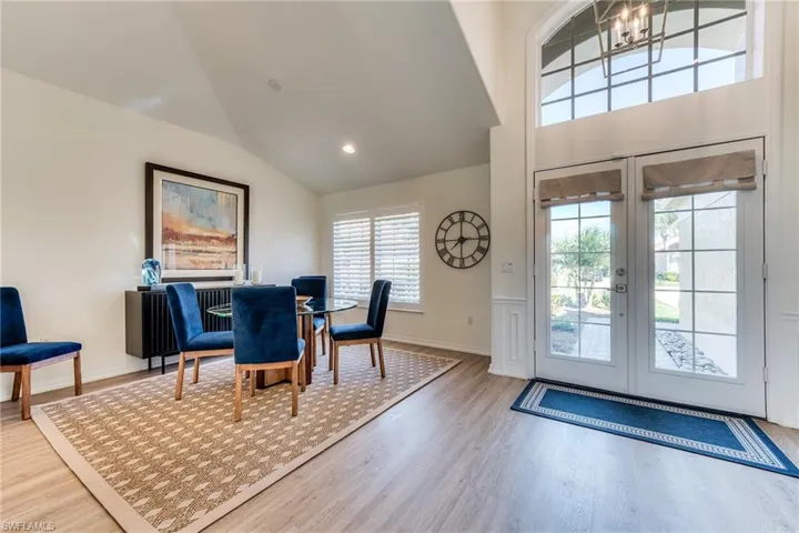 Foyer with french doors, a notable chandelier, lofted ceiling, recessed lighting, and wood finished floors