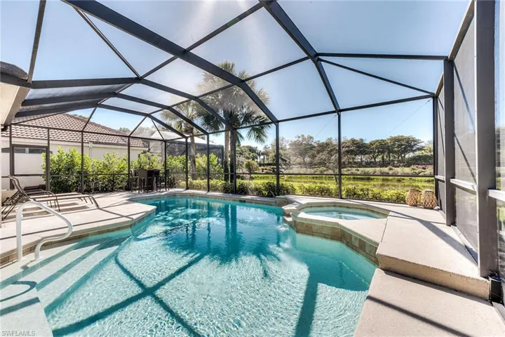 View of pool with a lanai, a pool with connected hot tub, and a patio