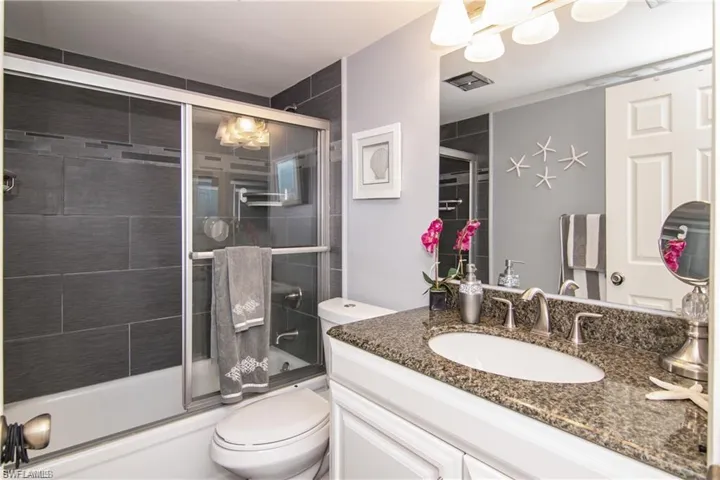 Bathroom featuring toilet, vanity, and bath / shower combo with glass door