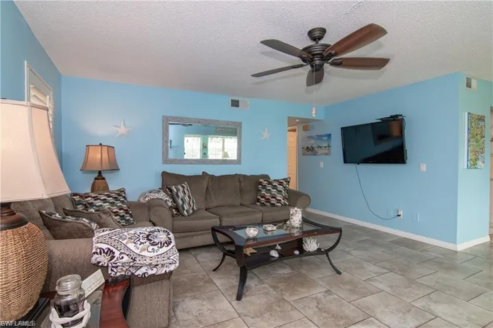 Living room featuring ceiling fan, a textured ceiling, and baseboards
