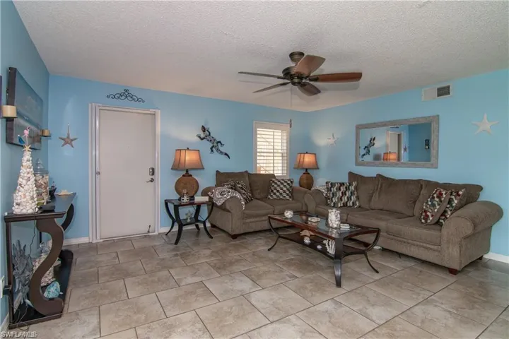 Living area with ceiling fan, a textured ceiling, and baseboards