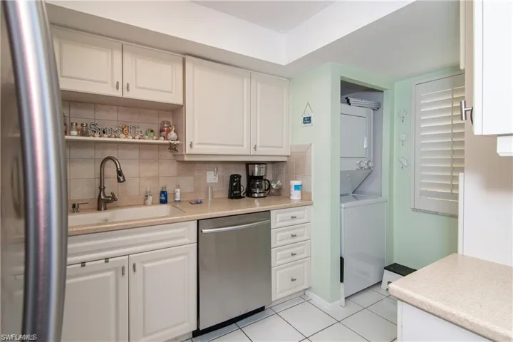 Kitchen featuring stainless steel appliances, a sink, stacked washer / dryer, and backsplash