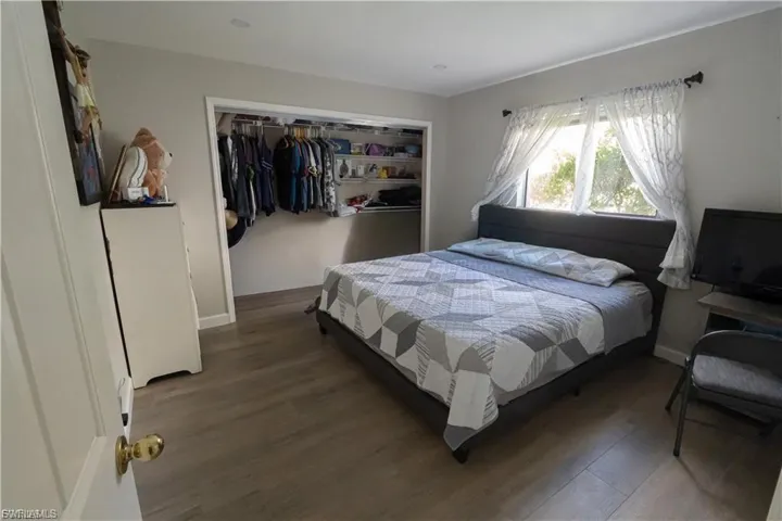 Spacious room featuring wood-finish flooring, a wide window with ample natural light, and a built-in closet with shelving and hanging rods