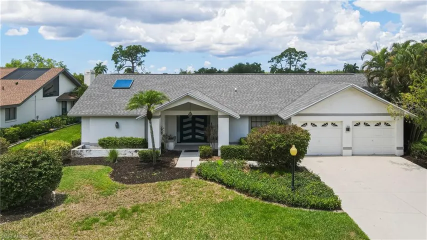 White stucco exterior with a gray shingle roof, featuring a skylight and a two-car garage