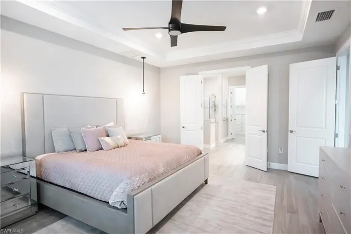 Bedroom featuring ceiling fan, a raised ceiling, ornamental molding, and light hardwood / wood-style floors