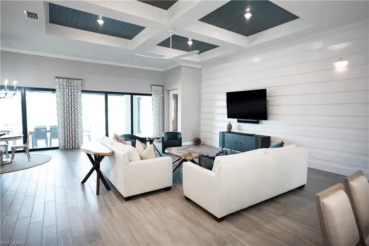 Living room with wood-type flooring, a high ceiling, ornamental molding, coffered ceiling, and beamed ceiling