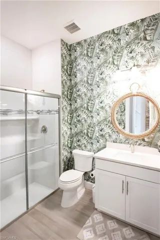 Bathroom with wood-type flooring, toilet, walk in shower, and vanity