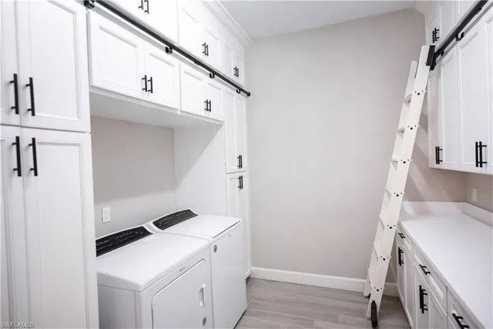 Washroom featuring a barn door, light hardwood / wood-style floors, cabinets, and independent washer and dryer