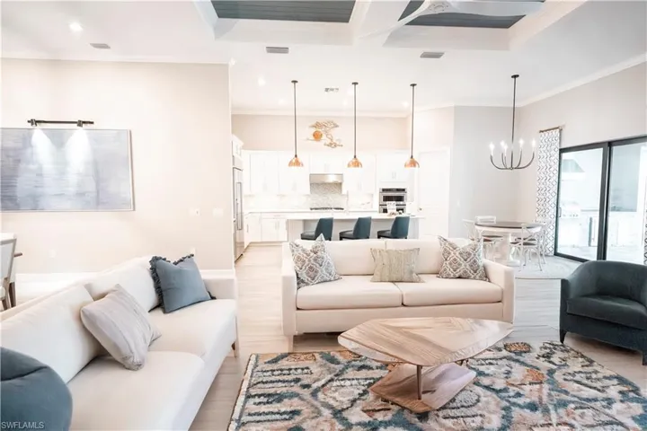 Living room with crown molding, light wood-type flooring, and a chandelier