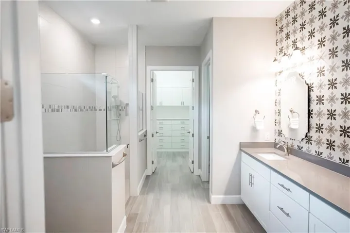Bathroom with a shower with shower door, wood-type flooring, and vanity