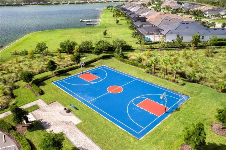 View of basketball court featuring a yard and a water view