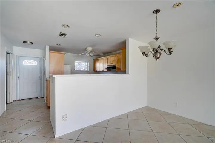 Kitchen featuring kitchen peninsula, hanging light fixtures, ceiling fan with notable chandelier, and light tile patterned floors