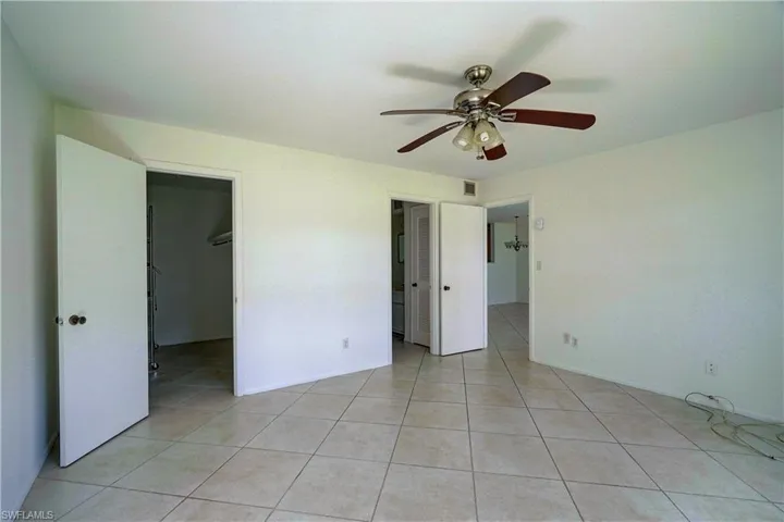 Unfurnished bedroom featuring a spacious closet, a closet, light tile patterned floors, and ceiling fan