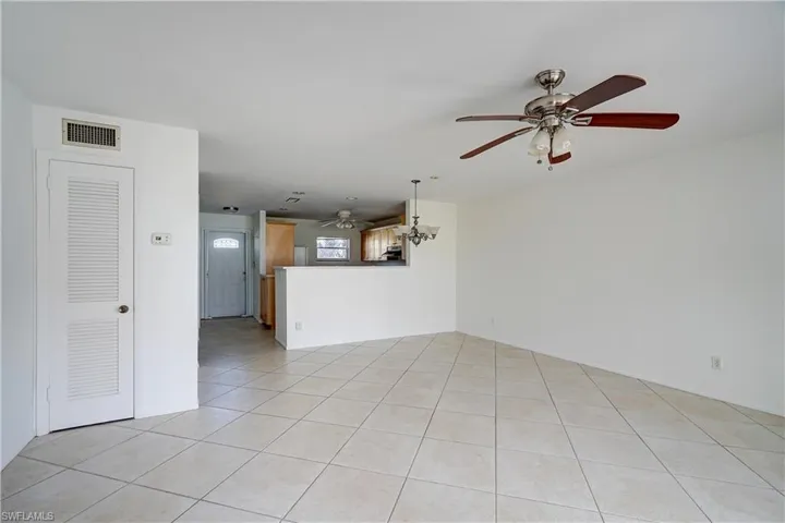 Unfurnished living room featuring a notable chandelier and light tile patterned flooring