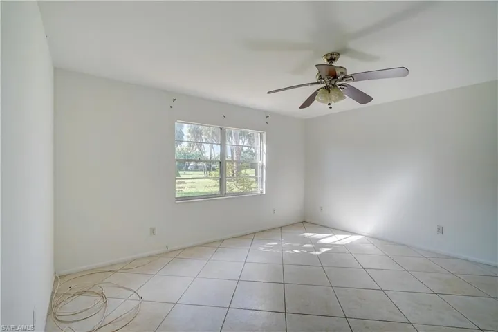 Tiled spare room featuring ceiling fan