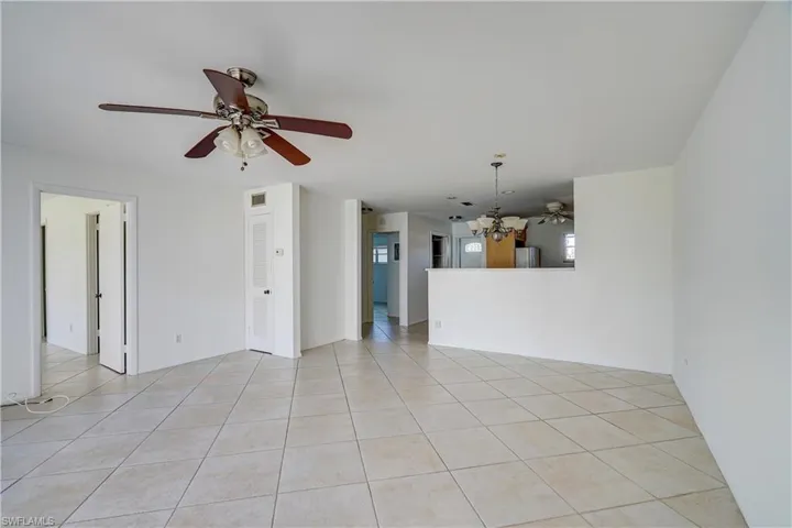 Tiled spare room with ceiling fan with notable chandelier