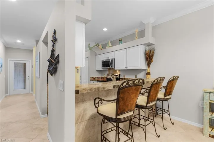 Kitchen with a breakfast bar, crown molding, white cabinetry, appliances with stainless steel finishes, and kitchen peninsula