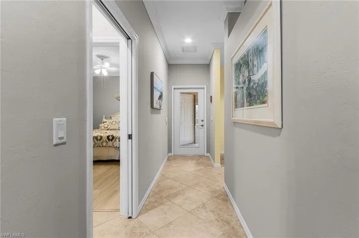 Corridor with crown molding and light tile patterned floors