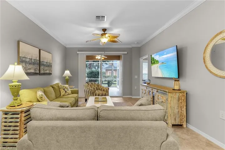 Living room with crown molding, light tile patterned flooring, and ceiling fan
