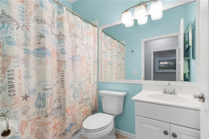 Bathroom with vanity, a shower with curtain, and toilet