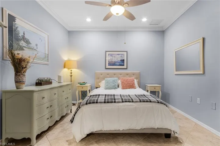 Bedroom with light tile patterned floors, ornamental molding, and ceiling fan