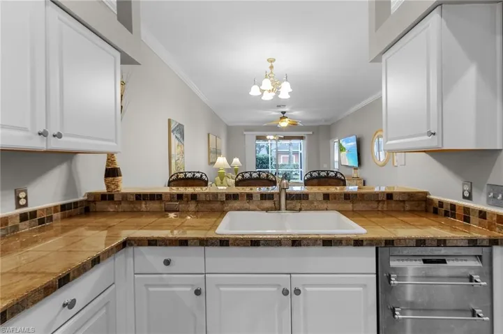 Kitchen featuring sink, crown molding, dishwashing machine, ceiling fan, and white cabinets