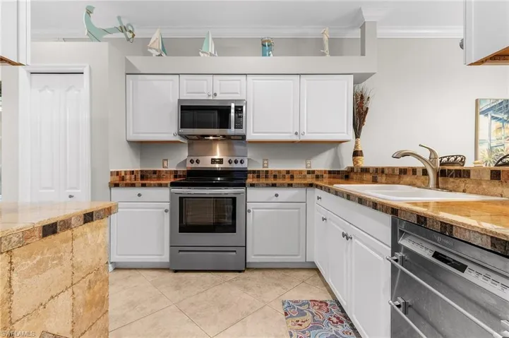 Kitchen featuring sink, crown molding, stone counters, white cabinetry, and stainless steel appliances