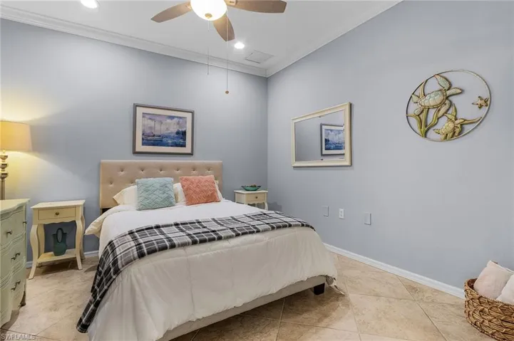 Tiled bedroom with ceiling fan and ornamental molding