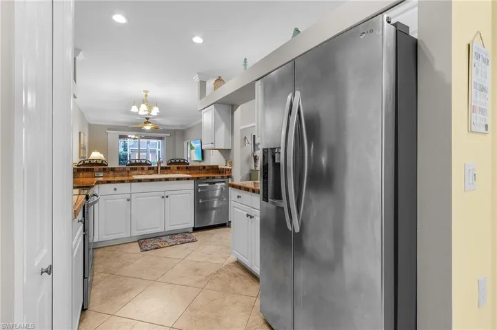 Kitchen with sink, ornamental molding, kitchen peninsula, stainless steel appliances, and white cabinets