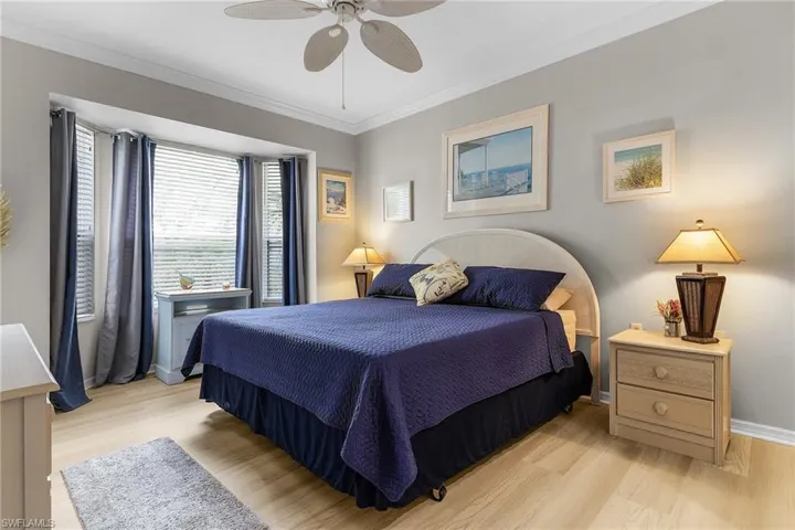 Bedroom with ceiling fan, ornamental molding, and light hardwood / wood-style floors