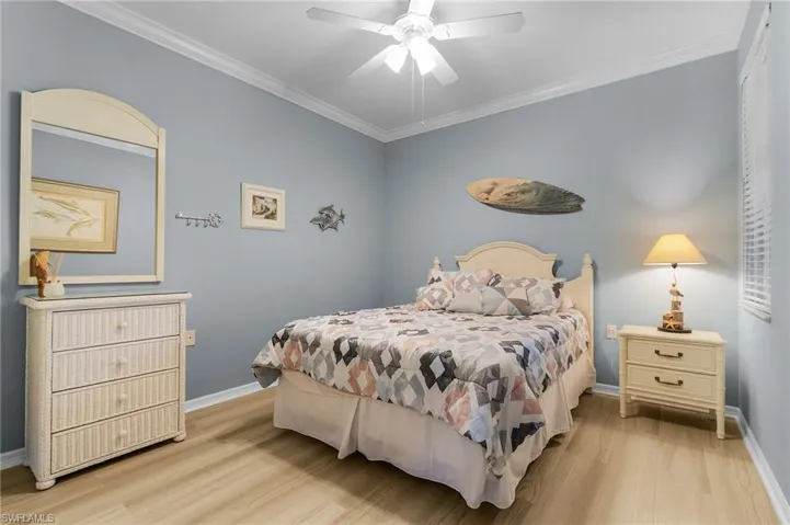 Bedroom with ornamental molding, light wood-type flooring, and ceiling fan